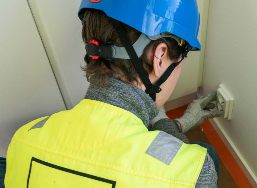 Sähkömies asentaa pistorasiaa